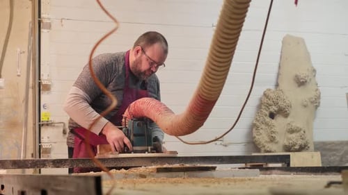 Carpenter Feeds Wood Through a Table Saw Hands Guiding with Expertise The Scene Underscores the