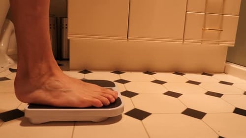 Wider side view of person stepping on and off scales with weight in kilograms
