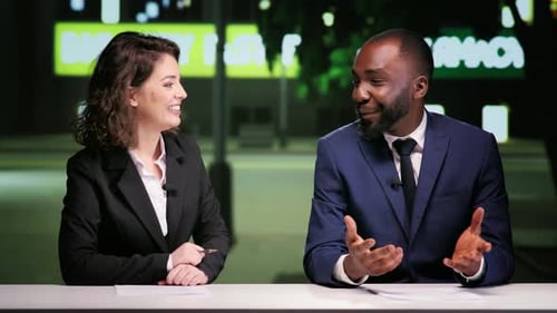 Smiling News Anchors Presenting a Broadcast at Night