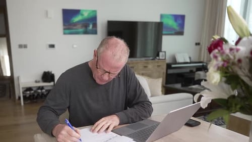Adult Working at Desk Using Laptop and Signing
