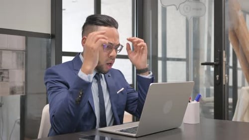 Man Typing at Laptop Looks Frustrated in Office