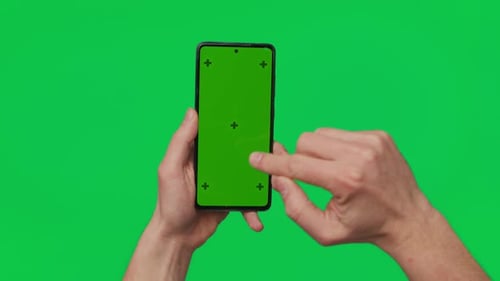 Male Hand Holding a Smartphone with Vertical Green Chroma Key Screen Isolated on Green Mobile Phone