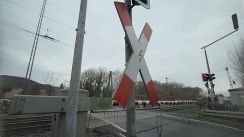 Trem passando por uma travessia ferroviária em um dia nublado com barreira fechada