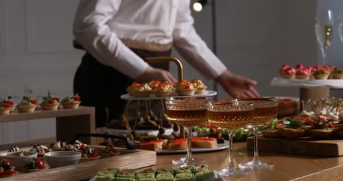 Waiter arranging appetizers for buffet at table, closeup