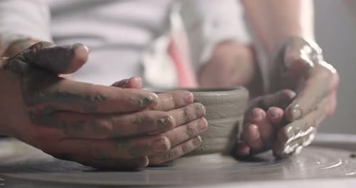 Child and Adult Make Pottery on a Wheel