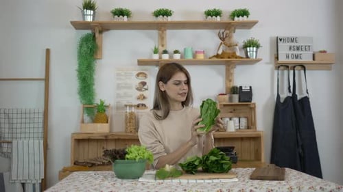 Woman Examines Lettuce in Rustic Home Kitchen