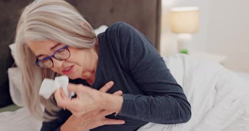 Senior Woman Coughing in Bed with Tissue