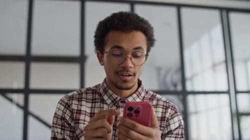 Young Adult Using Phone and Smiling Indoors