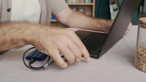Mann verbindet externe Festplatte mit Laptop