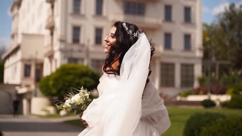 Bride Walks Smiling Holding Bouquet Outdoors
