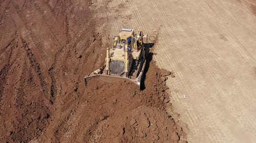 Bulldozer pushing large amount of fresh soil, Aerial follow footage.