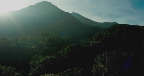 Cinematic Drone View of Sunlight Rays Over Tropical Mountain Forest