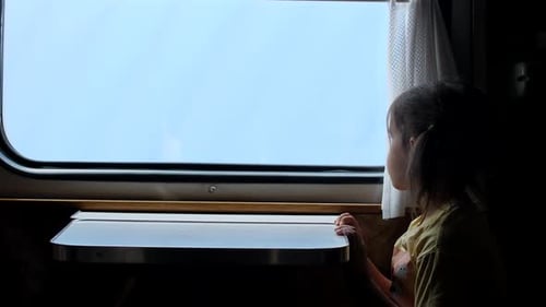 Little Girl Riding in Train Compartment Car and Looking Out Window