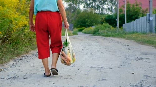 Senior Woman Walks with Fresh Vegetables