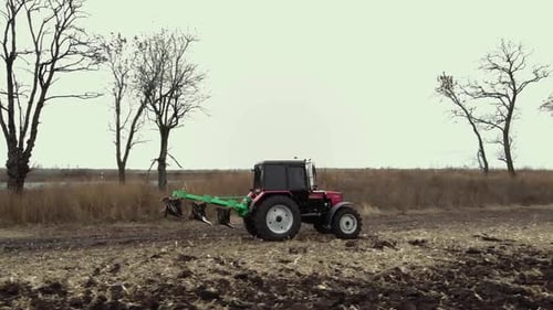 Red tractor plowing the field in Ukraine