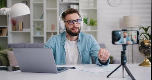 Un
popular bloguero con auriculares inalámbricos habla en una videollamada con su teléfono móvil. Influenciador