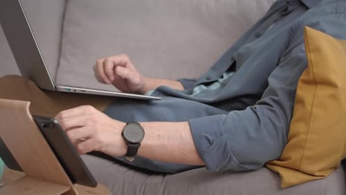 Man Relaxes at Home With Laptop and Tablet
