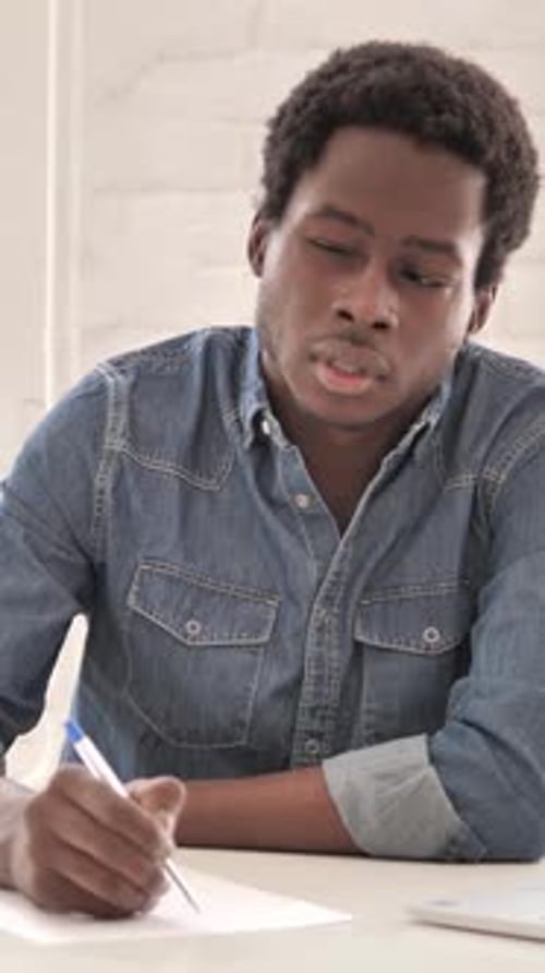 Thoughtful Man Writing on Paper at Table Indoors