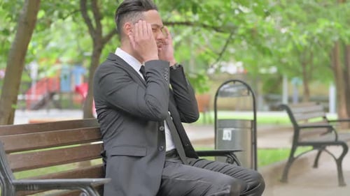 Stressed Businessman Sitting on a Park Bench