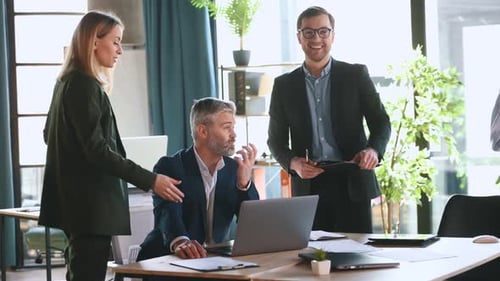 By the table, talking about project. Business people are working in the office together