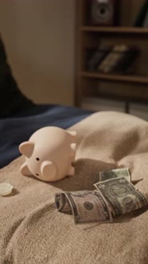 Piggy Bank and Dollar Banknotes Lying on Bed in Kids Bedroom
