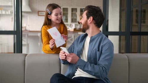 Girl Giving Father's Day Card to Happy Dad