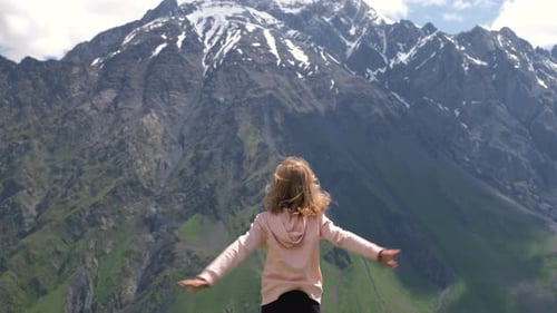 Girl Dancing in front of Beautiful Snow Mountains