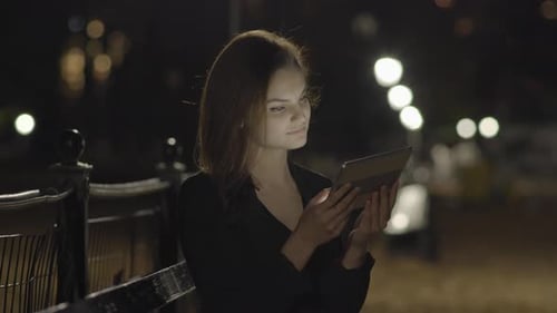 Young Woman Using Tablet Computer In The Park At Night
