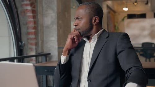 Man thinking at desk while using laptop