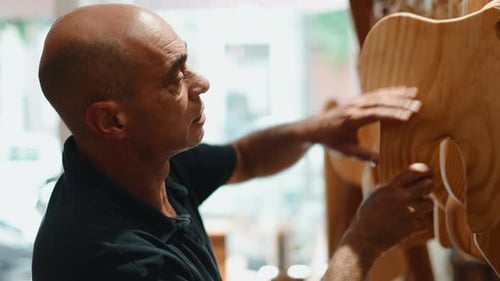 Artisan Guitar Maker Checking the Unfinished Wood Body in His Workshop