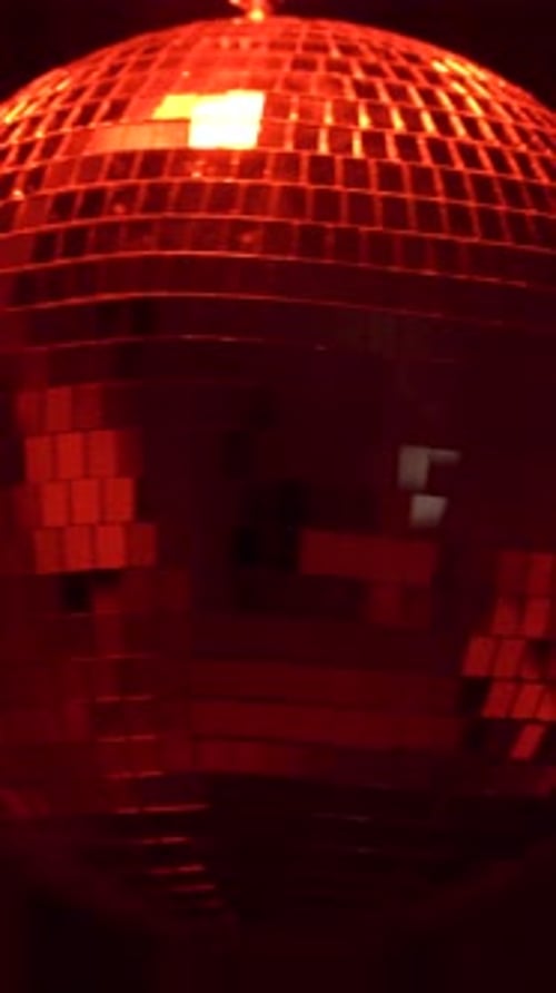Disco ball spins in vibrant light. Vertical
