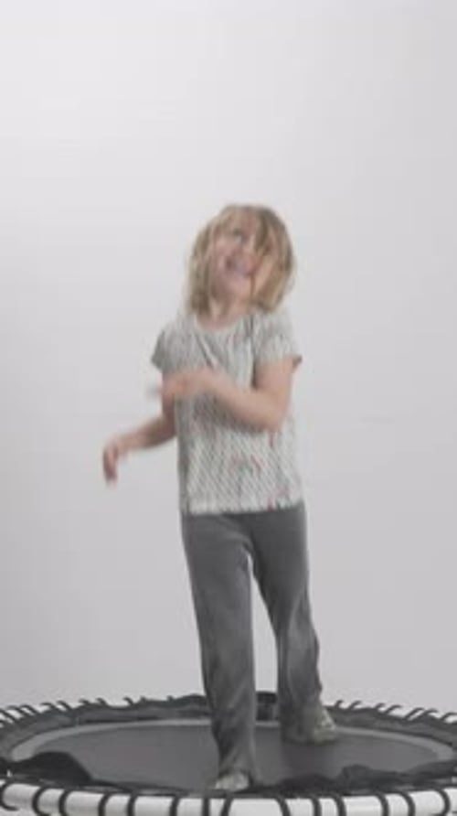 Happy Girl Jumping on Trampoline in Studio Setting