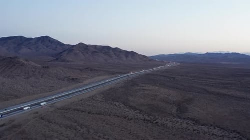 Aerial view of trucks driving on interstate highway crossing California desert landscape