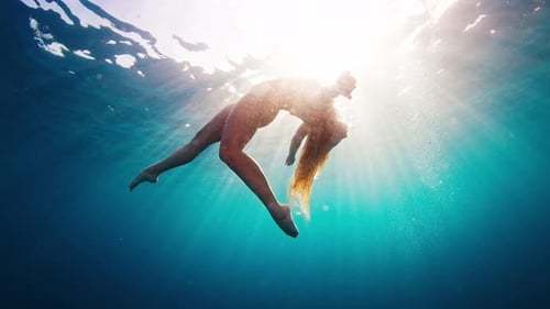 Teen Girl in Red Suit Dives and Swims Confidently Underwater in the Crystal Clear Tropical Sea