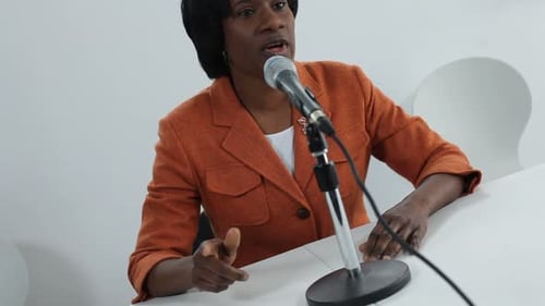 Woman Speaks at Microphone in Corporate Setting