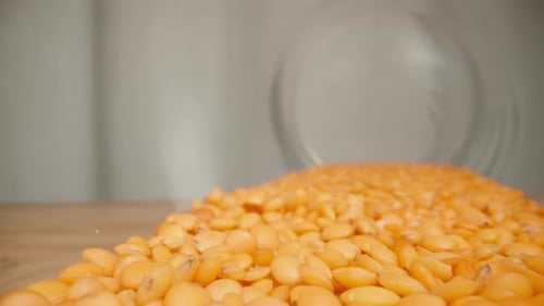 An overturned can of red lentils on a wooden table, from the inside. Dolly slider extreme close-up.