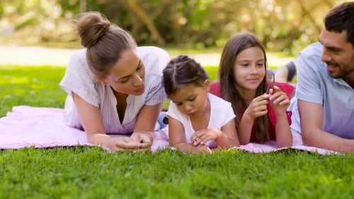 Family Lying on Blanket Together in Park on Lawn