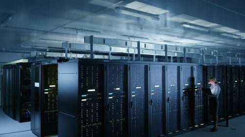 In Data Center: Female IT Technician Stands before Open Server Rack Cabinet, Uses Laptop Computer t