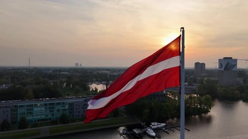 Waving National Flag Above City at Sunset