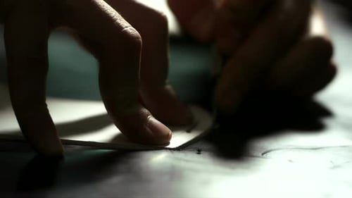 Lederarbeiterhände schneiden in der Werkstatt präzise Ledermuster mit einem Messer