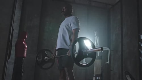 Man Lifting Weights in Dark Indoor Gym