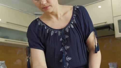 Woman Decorates Cake with Icing in Kitchen