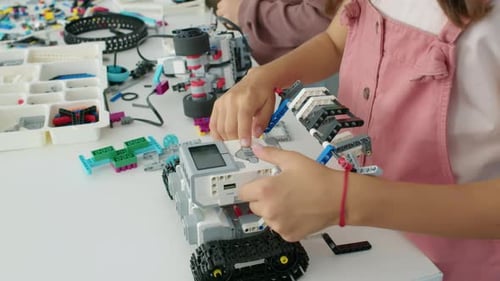 Manos de niña anónima presionando botones en modelo de robot eléctrico