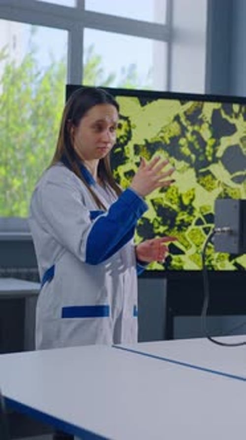 Woman Scientist Explains Science Near Microscope in Lab