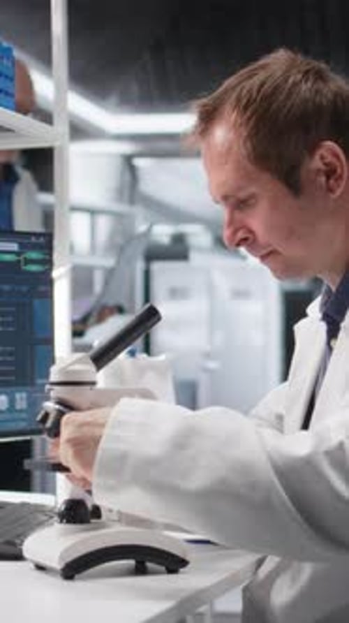 Man Uses Microscope in Bright Modern Research Lab