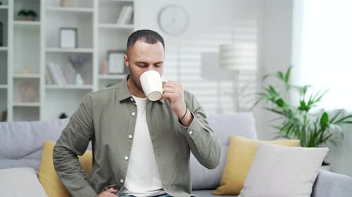 Man Enjoying Coffee Sitting on Couch at Home