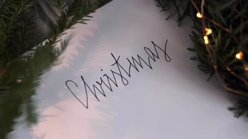 Weihnachten in Kursivschrift auf einer Grußkarte mit Kiefernblättern, Nahaufnahme