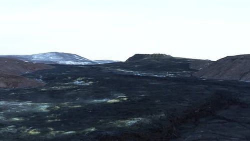 Large solid black lava field in Fagradalsfjall valley, distant dormant Geldingadalsgos volcano
