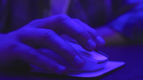 Souris masculine cliquant avec la main et assis au bureau travaillant en ligne au ralenti