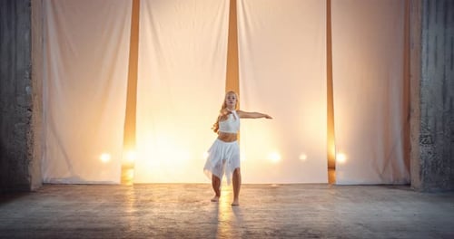 Young Woman Dancer in White Dress Performing in Studio Against White Backdrop